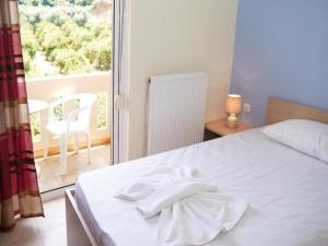 1 dormitorio con 1 cama con sábanas blancas y balcón en Joanna luxury apartment, en Fournés