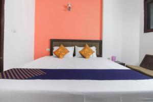 Goroomgo Viren Pacific Agra Near Taj Mahal - Wonderfull Stay with Family في آغْرا: غرفة نوم بسرير كبير بجدران برتقالية