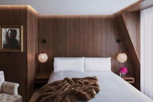 a bedroom with a white bed with a brown blanket at The London EDITION in London
