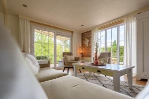 a living room with a white couch and a table at Prachtige vakantiewoning aan water met grote tuin in Voorthuizen