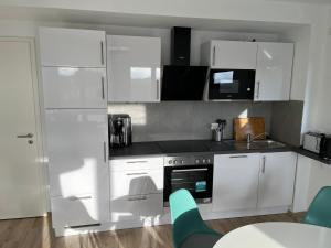 a kitchen with white cabinets and a table and chairs at The Fehmarn Lodges - EMOTION - in Fehmarn