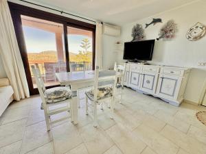 comedor con mesa, sillas y TV en Sea View Homes CB, en Baja Sardinia