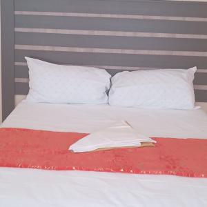 - un lit blanc avec des oreillers blancs et un livre dans l'établissement Sandton guesthouse, 