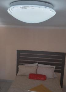 une lumière au-dessus d'un lit avec deux oreillers dans l'établissement Sandton guesthouse, 