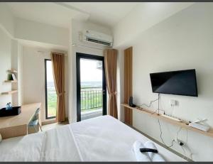 a bedroom with a bed and a flat screen tv at Capital O 93854 Apartemen Sayana By Sentra Jaya in Bekasi