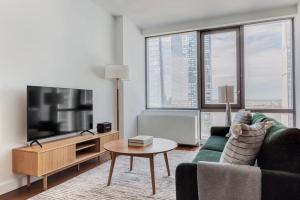 uma sala de estar com um sofá verde e uma televisão em Blueground Hudson Yards sports fitness wd NYC-1484 em Nova York