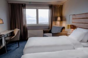 Habitación de hotel con cama, escritorio y ventana en Radisson Blu Polar Hotel, Spitsbergen en Longyearbyen