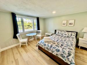 1 dormitorio con 1 cama, mesa y sillas en Sandy Neck Motel en Sandwich