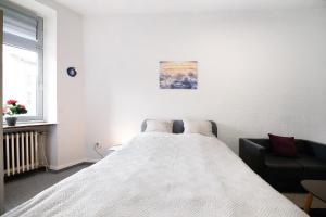 um quarto branco com uma cama e uma cadeira em Wendelin em Sankt Wendel