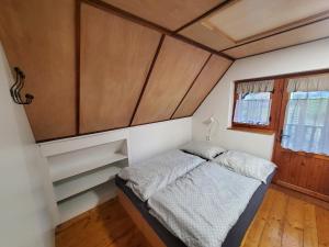 a small bedroom with a bed and a window at Chata Mezičky in Jiřetín pod Jedlovou