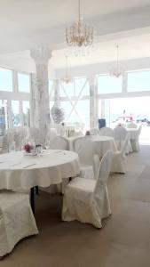 un restaurante con mesas y sillas blancas y una lámpara de araña en Studio at Elenite 20 m away from the beach with sea view shared pool and jacuzzi en Elenite
