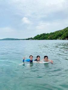 3 Personen schwimmen in einem Wasserkörper in der Unterkunft Family Room near Kawasan Falls in Matutinao
