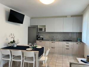una cocina con mesa y sillas y una cocina con armarios blancos. en Appartamenti Mare, en Lignano Sabbiadoro