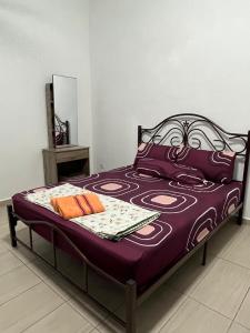 Cama en habitación con sábanas moradas y almohadas de color naranja en Homestay Angah, en Melaka