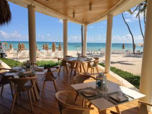 ein Restaurant am Strand mit Tischen und Stühlen in der Unterkunft Stunning 1-Bed Apartment pool view in Punta Cana in Punta Cana