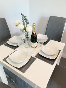 een tafel met witte borden en een fles wijn bij Rowlands Annex in Yelverton