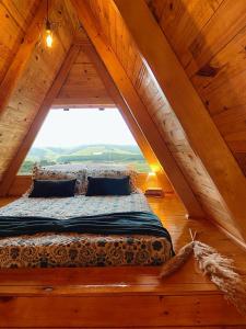 uma cama num quarto com uma grande janela em Chalés Recanto do Vale - GRALHA AZUL em Bom Jardim da Serra