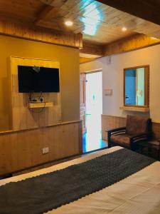 a bedroom with a flat screen tv on a wall at The Avenue River Side Hotel - Near Volvo Bus Stand Manali in Manāli