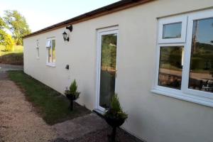 een wit huis met ramen en planten aan de zijkant bij Glenview Lodge accommodation, Monmouthshire in Usk