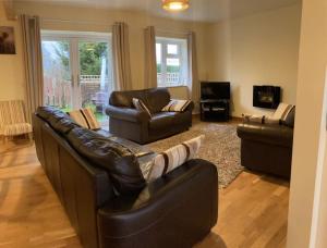 a living room with two leather couches and a television at Glenview Lodge accommodation, Monmouthshire in Usk