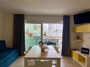 sala de estar con mesa y sofá azul en Appartamenti Mare, en Lignano Sabbiadoro