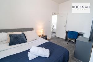 ein Schlafzimmer mit einem großen Bett mit einer blauen Decke in der Unterkunft Grove House 8 Bed Apartment Close To Beach with Parking by RockmanStays in Southend-on-Sea