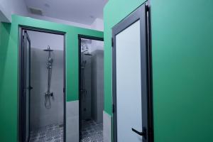 a bathroom with green walls and two glass doors at Nineties homestay in Hue