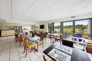 a dining room with tables and chairs and windows at All Suites La Teste – Bassin d’Arcachon in La Teste-de-Buch