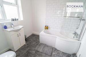 a white bathroom with a tub and a sink at 32 The Grove - Modern & Elegant Home Close to Beach with Parking by RockmanStays in Southend-on-Sea