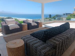 a group of couches sitting on a patio with the ocean at Haven On Hill in Plettenberg Bay