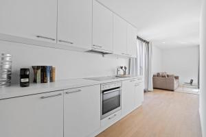 een witte keuken met een wastafel en een fornuis bij Boissonnet 96 Residence by Homenhancement in Lausanne
