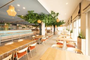 un restaurante con mesas de madera, sillas y plantas en BEECH Resort Boltenhagen en Boltenhagen