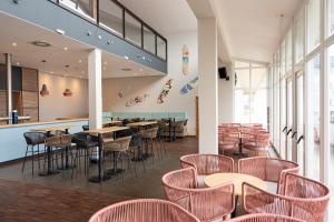 - un restaurant avec des tables et des chaises dans une salle dans l'établissement BEECH Resort Boltenhagen, à Boltenhagen