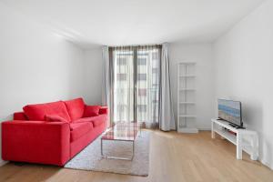 een woonkamer met een rode bank en een tv bij Boissonnet 96 Residence by Homenhancement in Lausanne
