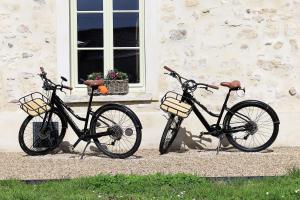 zwei Fahrräder, die neben einem Gebäude mit Fenster geparkt sind in der Unterkunft La petite châtelaine - Charmante maison au calme 