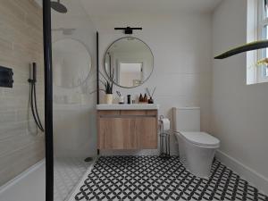 bagno con servizi igienici, lavandino e specchio di Modern large en suite loft room in Bromley, London a Bickley
