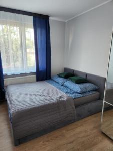 a bed with green pillows in a room with a window at Apartament Zeromskiego in Ostróda