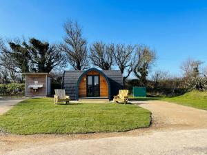 a small cabin with two chairs in front of it at Camping Pods Silver Sands Holiday Park in Lossiemouth