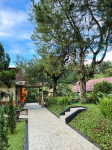une passerelle dans un jardin avec des arbres et une maison dans l'établissement Alamsagita Puncak Hotel & Resort, à Ciloto