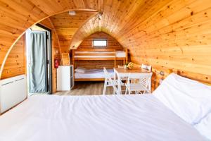 1 dormitorio en una cabaña de madera con 1 cama y 1 mesa en Camping Pods Silver Sands Holiday Park, en Lossiemouth