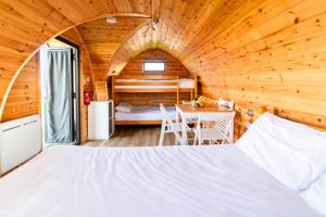 a bedroom in a log cabin with a bed and a table at Camping Pods Silver Sands Holiday Park in Lossiemouth