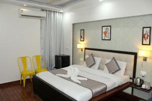 a bedroom with a large bed with two yellow chairs at Hotel Krishna Residency Bareilly Near Ashish Royal Park in Bareilly