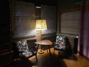 a room with two chairs and a table and a lamp at Садиба Модрина in Velyka Volosyanka
