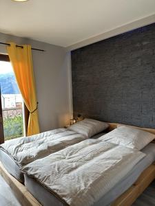 a large bed in a bedroom with a brick wall at Casa Di Tino by GadraDoma in Assenza di Brenzone