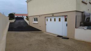 a garage with two white doors on a building at Le Studio in Saint-Martin-des-Tilleuls