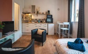 a living room with a kitchen with a couch and a chair at Le petit chez vous - T1 Bergerac -2 pers in Bergerac