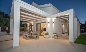 een witte patio met een tafel en stoelen bij Villa MANDI & JANI by "elite" in Laganas