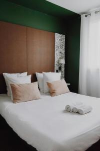a large white bed with two towels on it at L'Hôtel Bristol in Caen