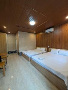 a bedroom with two beds and a wooden wall at Biển Xanh Homestay in Ly Son