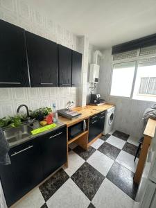 a kitchen with black cabinets and a checkered floor at Habitación 3 - 3 planta sin ascensor in Fuengirola